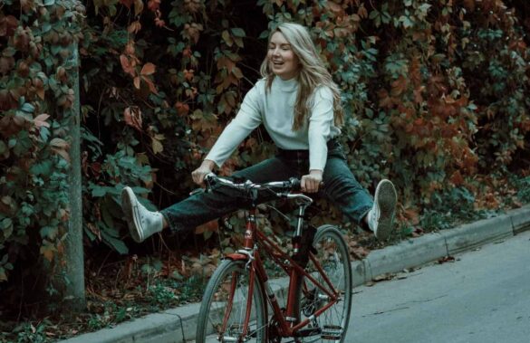 woman in white long sleeve shirt riding on black bicycle on road during daytime