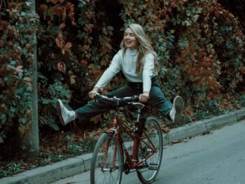 woman in white long sleeve shirt riding on black bicycle on road during daytime